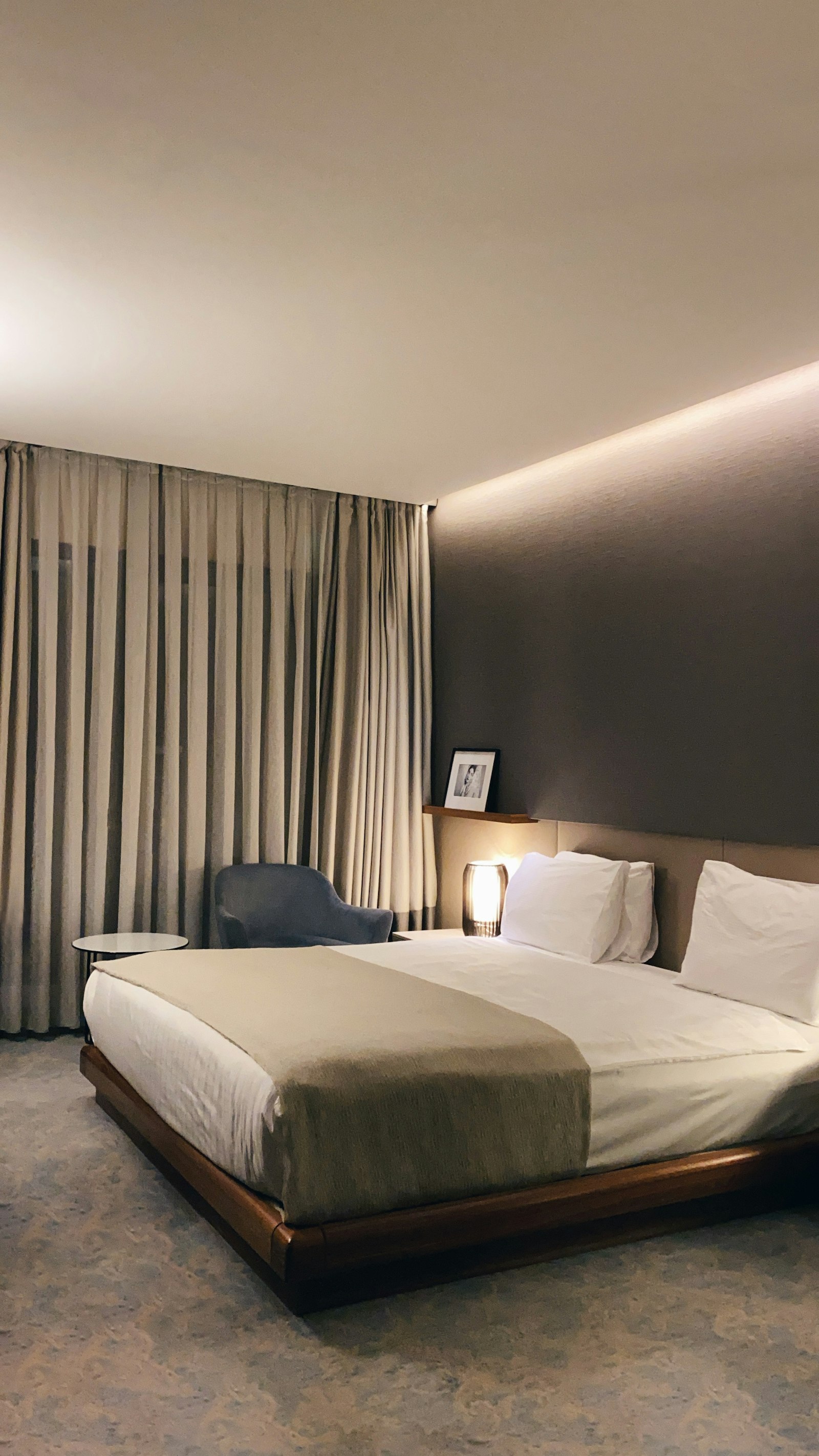 A quiet hotel room, one lamp lit, curtain wall drawn